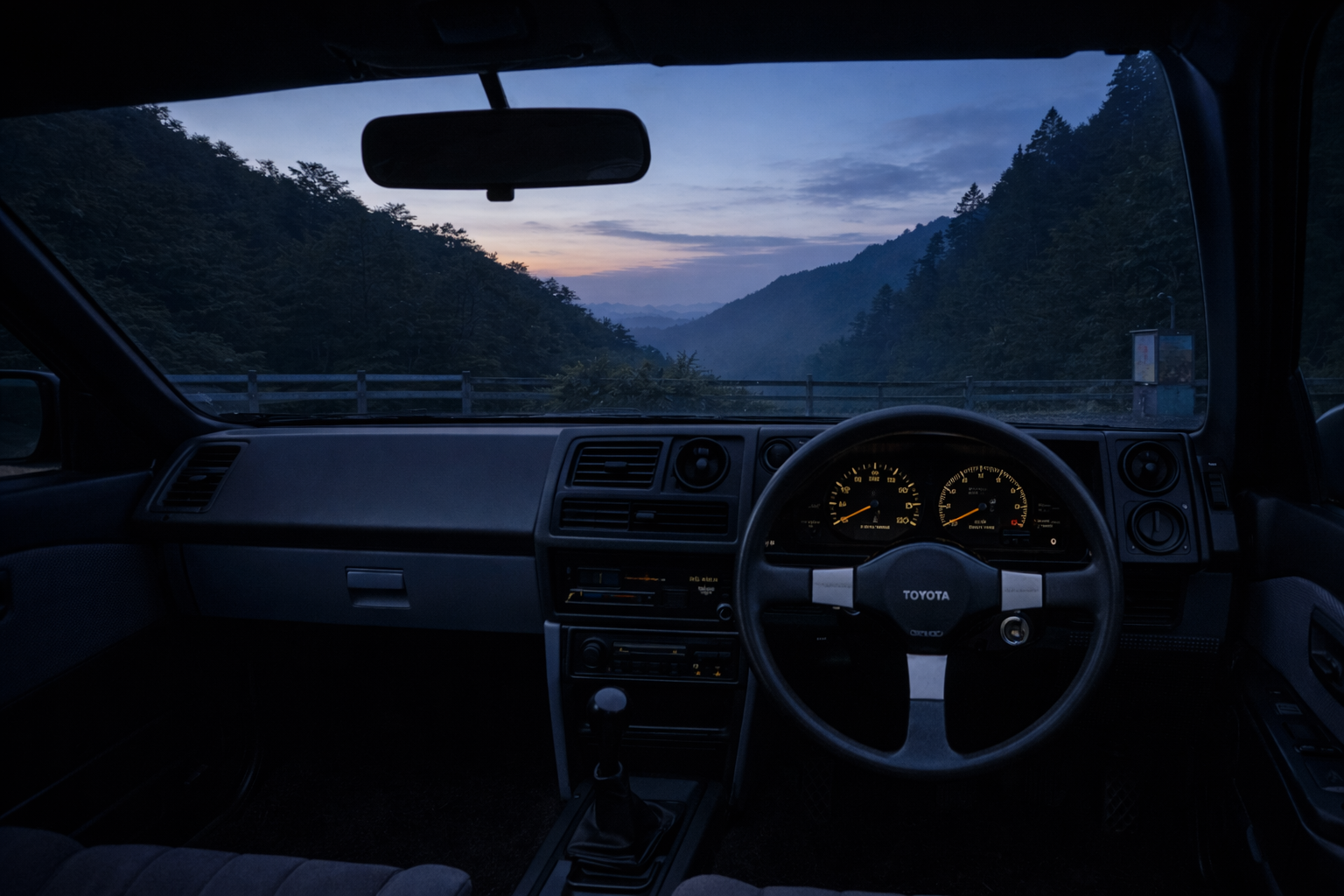 Inside a Toyota AE86 after the engine has been shut off, just before dawn. Silence fills the mountain pass as the gauges softly glow.
